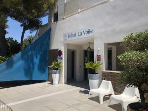 a building with two white chairs in front of it at Hotel La Voile in Bormes-les-Mimosas