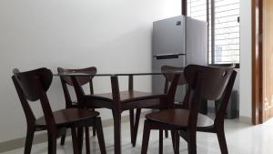 a dining room table with chairs and a refrigerator at Sufia House Apartment in Dhaka