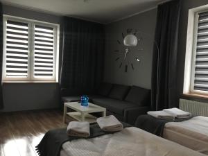 Pokój z dwoma łóżkami, kanapą i zegarem w obiekcie Apartament Elbląg Centrum w Elblągu