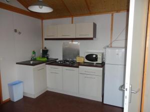 eine Küche mit weißen Schränken und einem weißen Kühlschrank in der Unterkunft clos du celine in Castillonnès