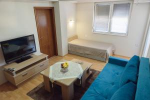 a living room with a blue couch and a television at City Center Apartments in Strumica