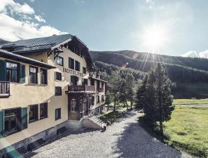 um hotel nas montanhas com o sol ao fundo em Hotel Fex em Sils Maria