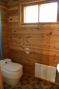 a bathroom in a log cabin with a toilet and a window at Paltto Elämysretket in Lemmenjoki