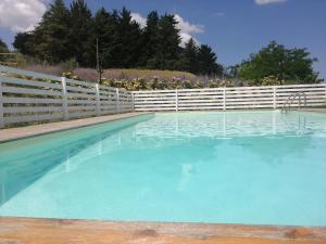 a swimming pool with blue water and a white fence at Il Gelso Country House in Castorano