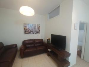 a living room with a couch and a flat screen tv at Lovely apartment premium location in Ramat Gan
