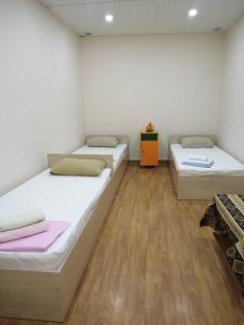 two beds in a room with wooden floors at REST Guest House in Yerevan