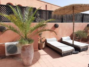 a patio with two beds and an umbrella at RIAD PÉNÉLOPE Marrakech in Marrakesh
