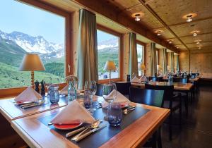 a restaurant with tables and chairs with mountains in the background at Hotel Stoffel - adults only in Arosa