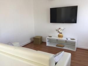 a living room with a white couch and a flat screen tv at maison proche du Mont Saint Michel in Pontorson