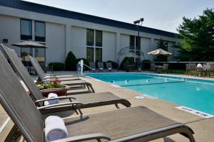 einen Pool mit Chaiselongues neben einem Hotel in der Unterkunft Greenstay Hotel & Suites Central in Springfield