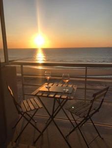 a table with two glasses of wine on a balcony with the ocean at Studio Manager in Middelkerke