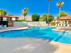 a large swimming pool with chairs and palm trees at Desert Getaway in Desert Hot Springs