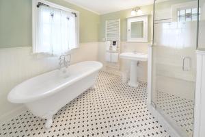 a white bathroom with a tub and a sink at The Springwater Bed and Breakfast in Saratoga Springs