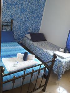 two beds in a room with blue wallpaper at B&B Odeon in Taormina