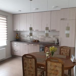 Apartamenti Danna في Lēdmane: مطبخ مع طاولة وكراسي ومطبخ مع دواليب بيضاء