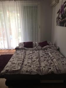 a bed with a comforter and pillows in a bedroom at ROSE Apartman in Debrecen