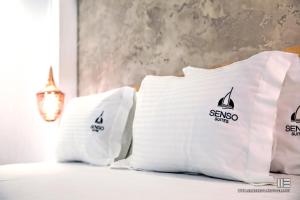 a bed with white pillows with a sailboat on them at Senso Suites in Nea Peramos