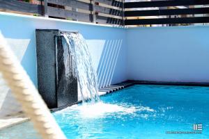 a swimming pool with a waterfall in a building at Senso Suites in Nea Peramos