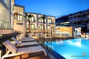 a swimming pool with lounge chairs and a building at Senso Suites in Nea Peramos