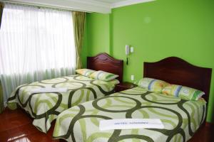 2 camas en una habitación con paredes verdes en Hotel Londres en Pasto