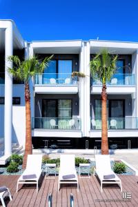 a group of chairs and palm trees in front of a building at Senso Suites in Nea Peramos