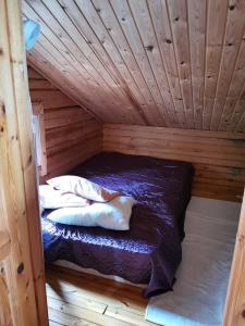 a bed in a wooden room with a wooden ceiling at Pistoretki Toivakka in Toivakka