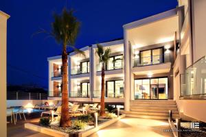 a building with palm trees in front of it at night at Senso Suites in Nea Peramos