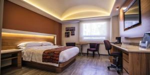 a hotel room with a bed and a desk at JF Grand Puebla in Puebla