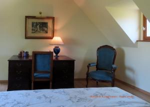 a bedroom with two chairs and a table and a bed at Rose cottage in Pontrieux