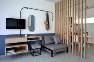 sala de estar con silla y TV en Voula Seaside Apartments, en Kallithea Halkidikis