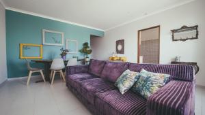 un sofá púrpura en una sala de estar con mesa en Vila Milreu Guest House, en Estói