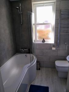 a bathroom with a tub and a toilet and a window at Tressell in Hastings