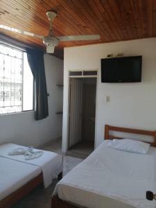 a bedroom with two beds and a flat screen tv at HOTEL LA QUINTA in La Dorada