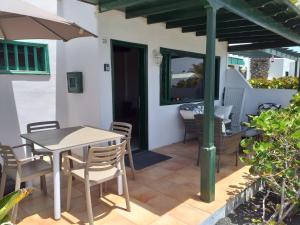 eine Terrasse mit einem Tisch, Stühlen und einem Sonnenschirm in der Unterkunft Bungalow DALAI - Pool view- Good wifi in Puerto del Carmen