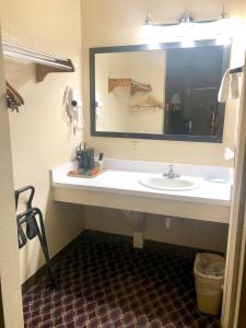 a bathroom with a sink and a large mirror at Economy Inn McCook in McCook