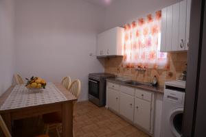 a kitchen with white cabinets and a table with a bowl of fruit at Margaret House in Isterni