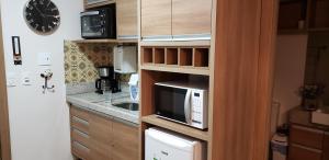 a kitchen with a microwave and a sink at Flat em Pedra Azul in Pedra Azul