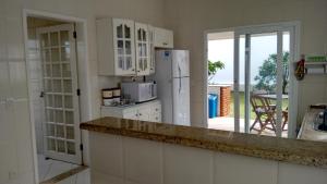 a kitchen with white cabinets and a counter with a refrigerator at CASA - FRENTE PARA O MAR in Itanhaém +74 photos