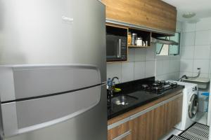 La cuisine est équipée d'un réfrigérateur, d'un évier et d'une cuisinière. dans l'établissement VERANO PONTA NEGRA AP1807, à Natal