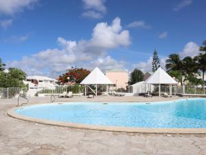 a large swimming pool with white umbrellas and chairs at BlueDreamVacances Marines IV in Saint-François