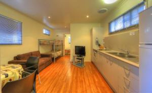 a kitchen and living room with a couch and a sink at Kookaburra Holiday Park in Cardwell