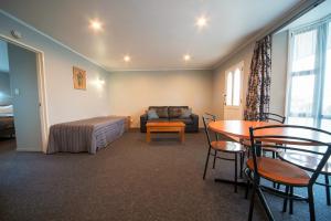 um quarto com uma cama, uma mesa e um sofá em Coronation Park Motels em Ashburton