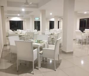a dining room with white tables and white chairs at Royale Chulan Cherating Chalet in Cherating