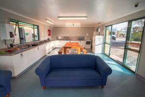 a large kitchen with a blue couch and a table at Coronation Park Holiday Park in Ashburton