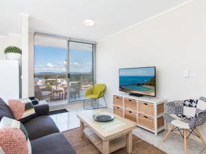a living room with a couch and a tv at Oceanic 26 in Forster