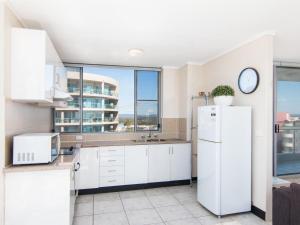 a kitchen with a refrigerator and a clock on the wall at Oceanic 26 in Forster