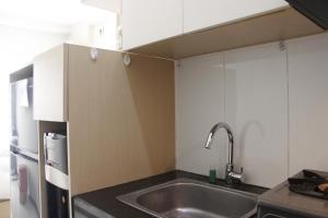 a kitchen with a sink and a refrigerator at Homey Studio Gateway Pasteur Apartment near Exit Toll By Travelio in Bandung