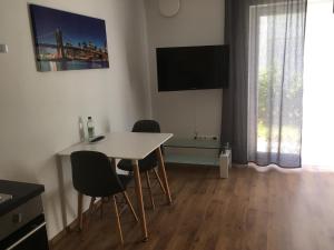 sala de estar con mesa, sillas y TV en Pension Sonntag Ferienwohnungen en Ingolstadt