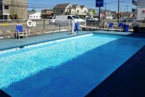 a blue swimming pool with blue chairs in a city at AIRE Hotel North Beach Jersey Shore in Seaside Heights
