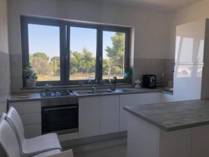 a kitchen with white cabinets and a large window at Roseto Mare B&B in Roseto Capo Spulico